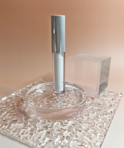 Professional eyelash extension glue in clear tube with silver cap premium adhesive for false lashes on luxury glass display